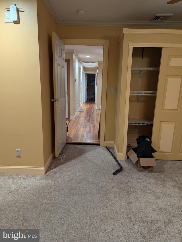hall with carpet, visible vents, baseboards, and crown molding