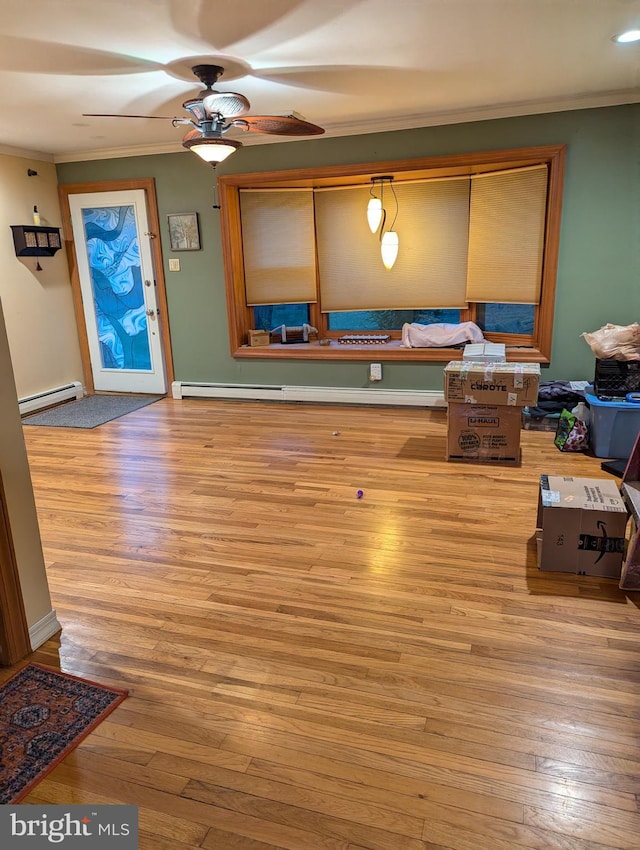 interior space with hardwood / wood-style floors, a baseboard heating unit, crown molding, and a ceiling fan
