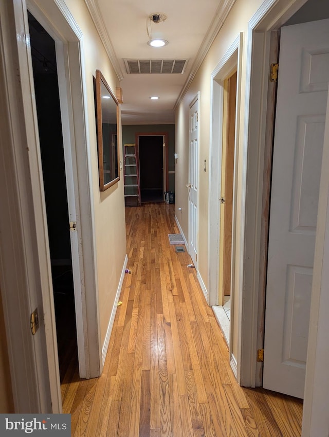 corridor with ornamental molding, visible vents, recessed lighting, light wood finished floors, and baseboards