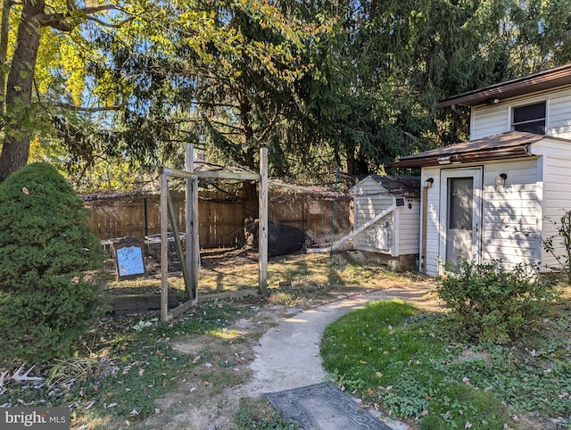 view of yard featuring a storage shed, fence, and an outdoor structure