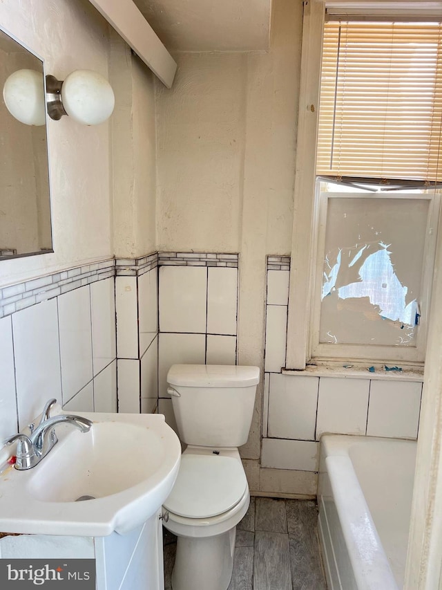 bathroom with vanity, a bathtub, toilet, tile walls, and hardwood / wood-style floors