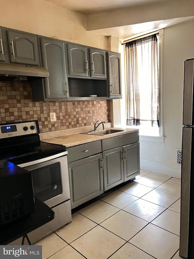 kitchen with sink, gray cabinetry, stainless steel appliances, backsplash, and light tile patterned floors