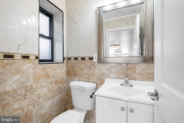 bathroom featuring vanity, tile walls, and toilet