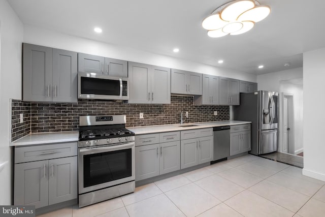 kitchen featuring sink, gray cabinetry, backsplash, appliances with stainless steel finishes, and light tile patterned floors