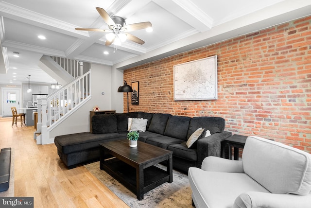 living room featuring ornamental molding, light hardwood / wood-style floors, beam ceiling, and brick wall