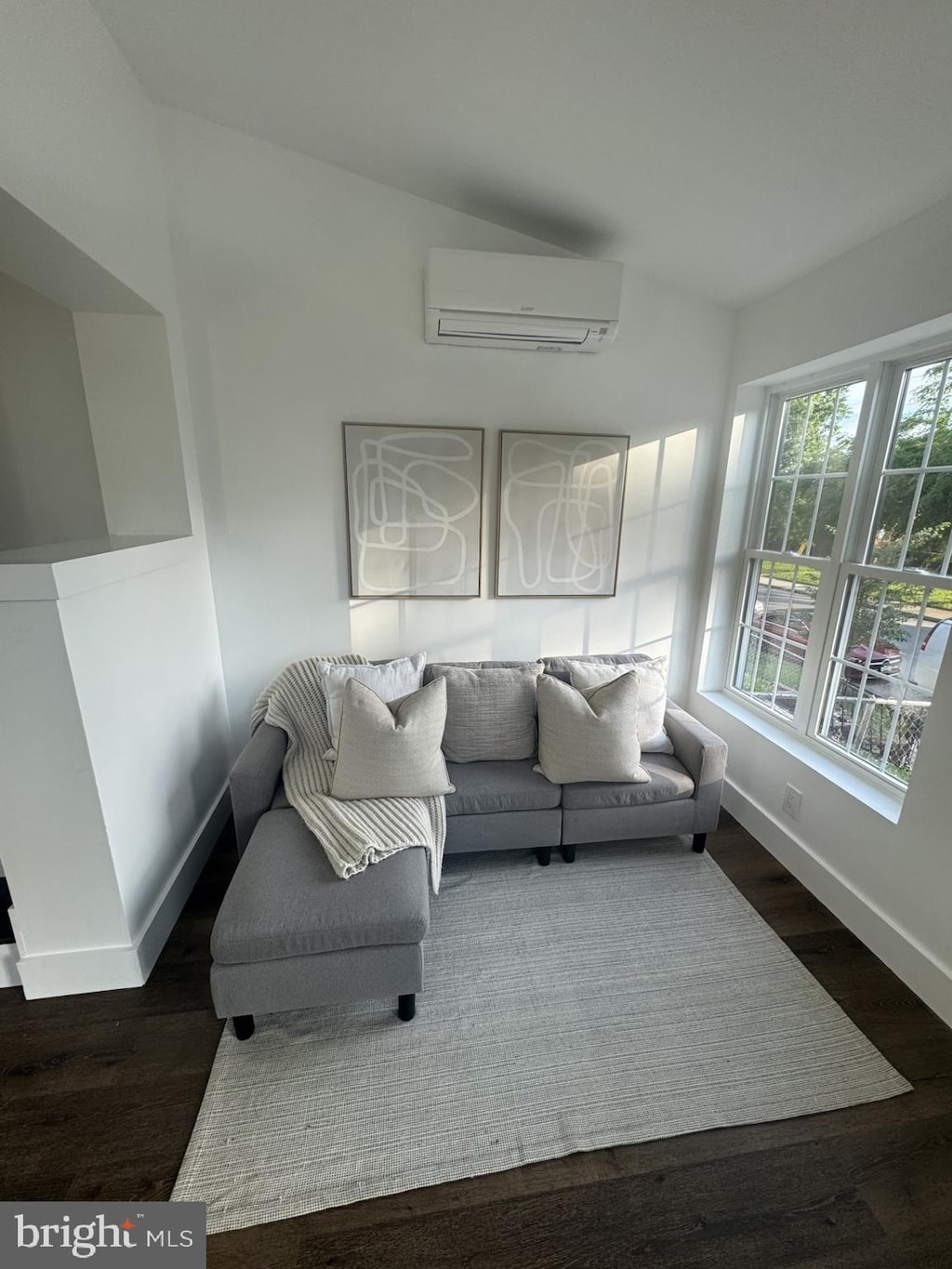 living room featuring dark hardwood / wood-style flooring and a wall mounted AC