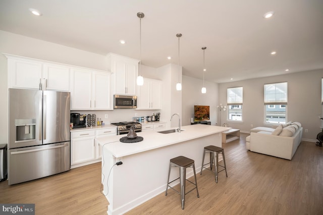 kitchen with white cabinets, a kitchen island with sink, stainless steel appliances, and a kitchen breakfast bar