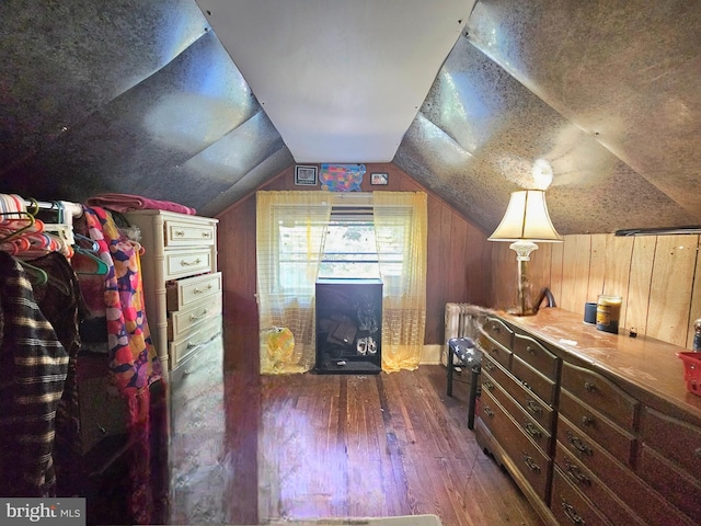 additional living space featuring vaulted ceiling, dark hardwood / wood-style flooring, and wooden walls