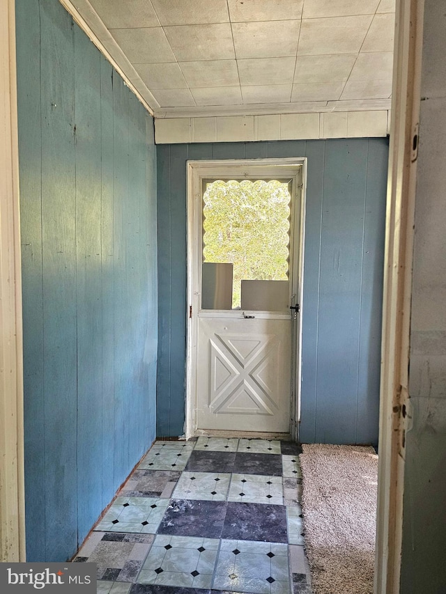 doorway to outside with wooden walls