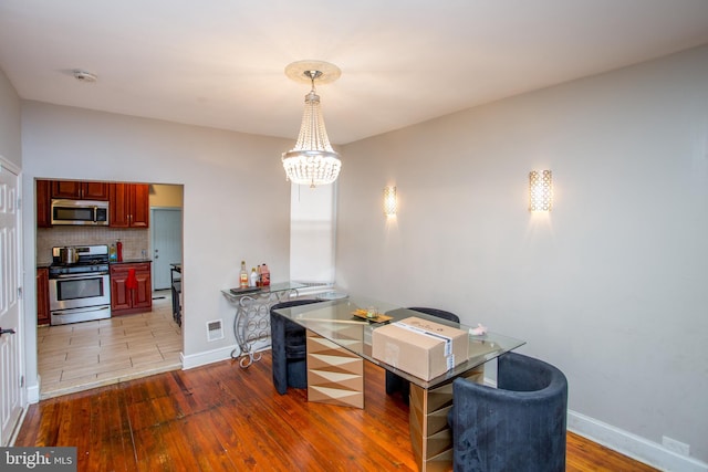 dining space with light wood-type flooring and a chandelier