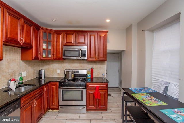 kitchen featuring backsplash, stainless steel appliances, dark stone countertops, and sink