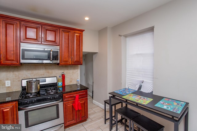 kitchen with appliances with stainless steel finishes, dark stone countertops, and tasteful backsplash