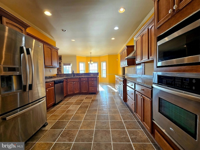 kitchen with a notable chandelier, dark tile patterned flooring, wall chimney exhaust hood, appliances with stainless steel finishes, and decorative light fixtures