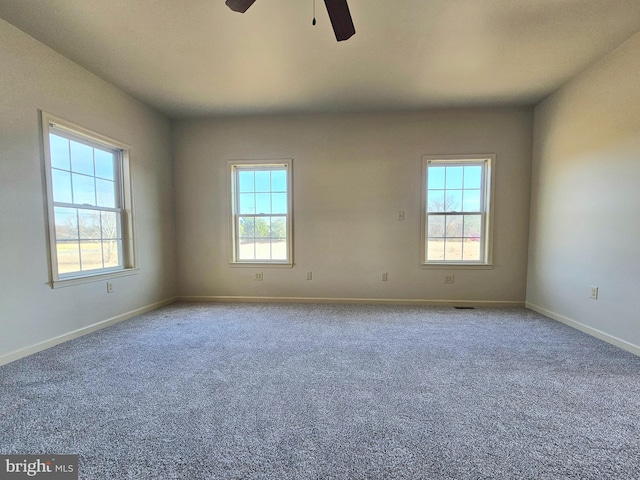 carpeted spare room featuring a wealth of natural light and ceiling fan