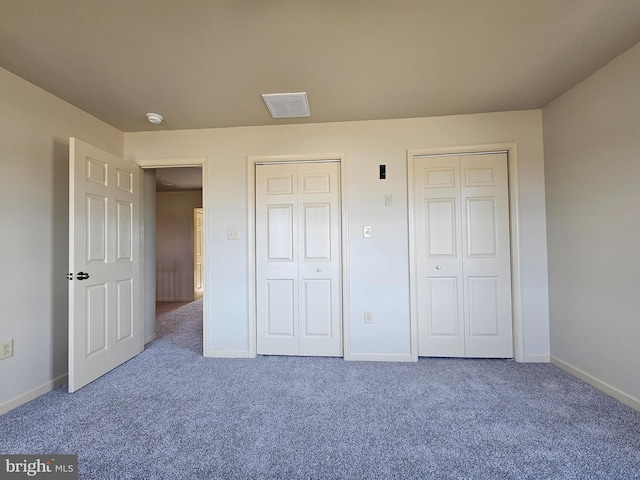 unfurnished bedroom featuring carpet flooring and two closets