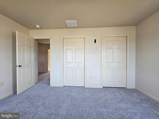 unfurnished bedroom with carpet flooring and two closets