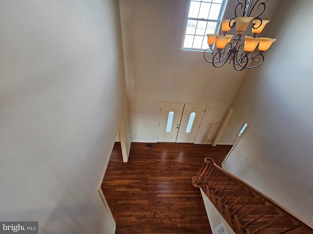 foyer entrance featuring dark hardwood / wood-style floors, a towering ceiling, and an inviting chandelier