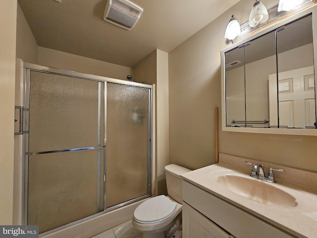 bathroom featuring tile patterned flooring, vanity, toilet, and a shower with door