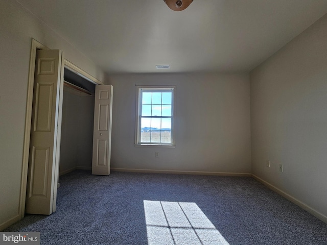 unfurnished bedroom featuring a closet and dark colored carpet