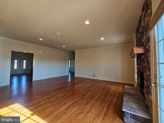 unfurnished living room with a stone fireplace, dark hardwood / wood-style flooring, and ornamental molding