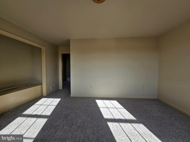 unfurnished room featuring dark carpet