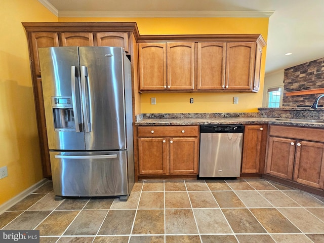 kitchen featuring sink, ornamental molding, stainless steel appliances, and dark stone counters