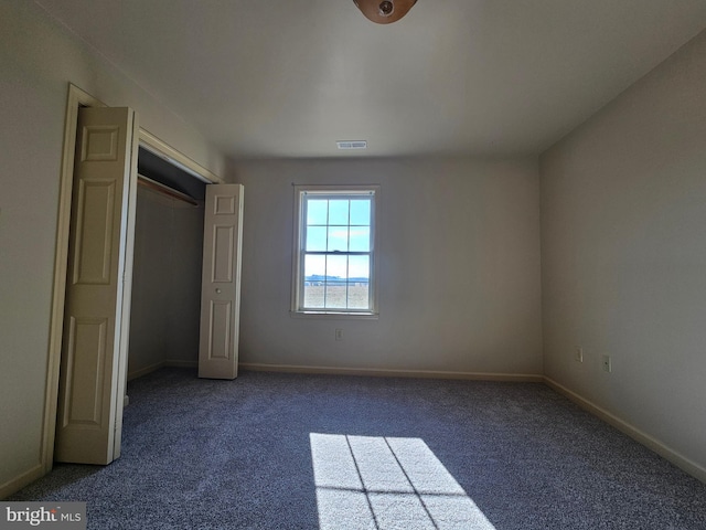 unfurnished bedroom with a closet and dark colored carpet