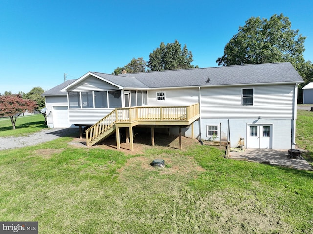 back of property featuring a deck, a yard, and a sunroom