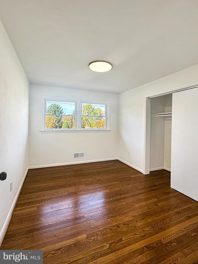 unfurnished bedroom with a closet and dark wood-type flooring