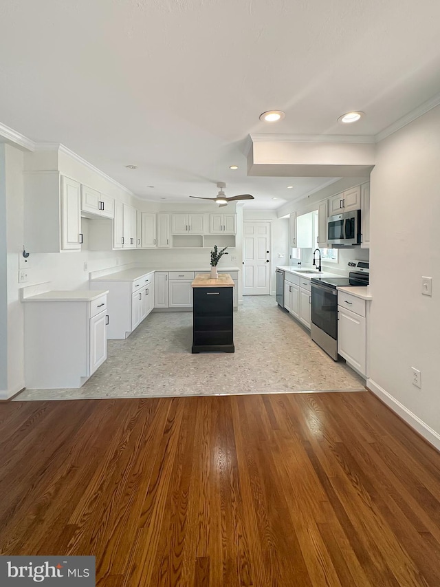 kitchen with stainless steel appliances, ceiling fan, sink, white cabinets, and light hardwood / wood-style floors