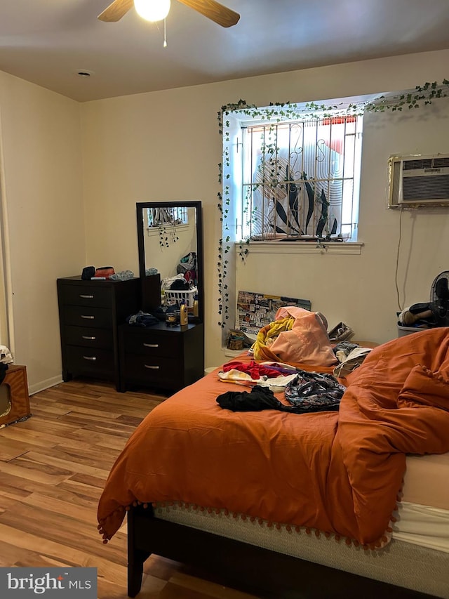 bedroom featuring ceiling fan, light hardwood / wood-style flooring, and a wall unit AC