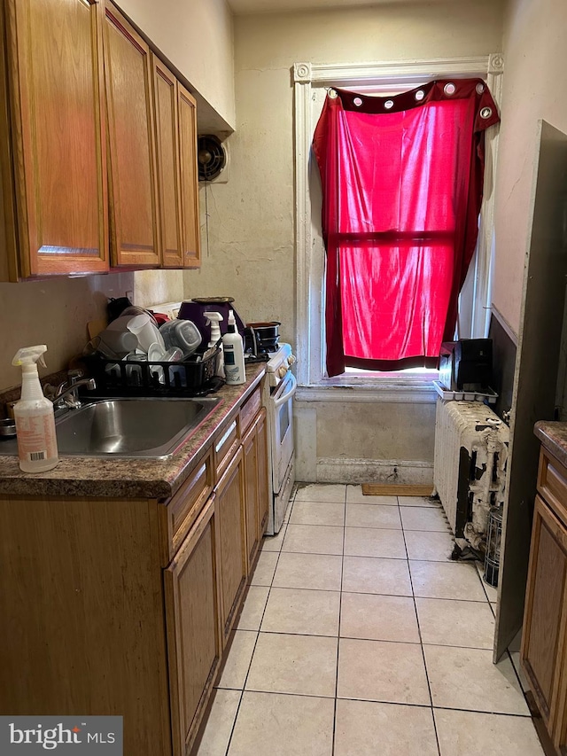 kitchen with white stove, sink, and light tile patterned floors