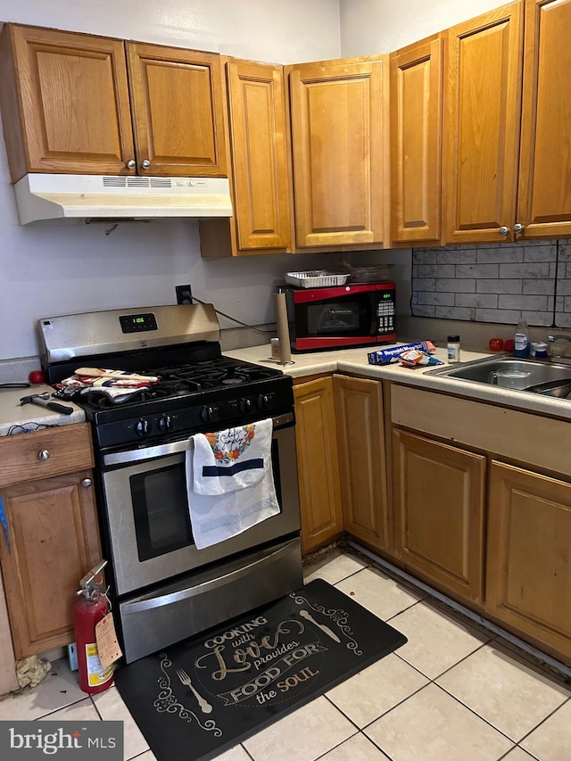 kitchen featuring stainless steel range with gas cooktop, sink, light tile patterned floors, and tasteful backsplash