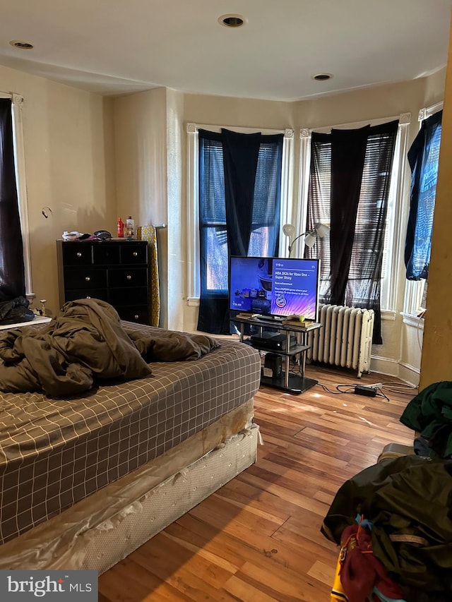 bedroom with hardwood / wood-style floors and radiator heating unit