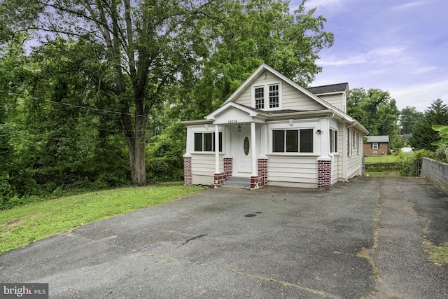 view of front facade featuring driveway, brick siding, and fence