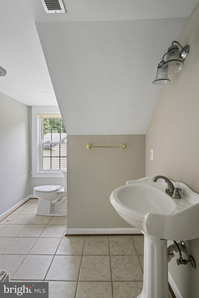 bathroom featuring lofted ceiling, tile patterned flooring, toilet, and baseboards