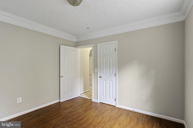 unfurnished bedroom featuring crown molding, a textured ceiling, baseboards, and wood finished floors