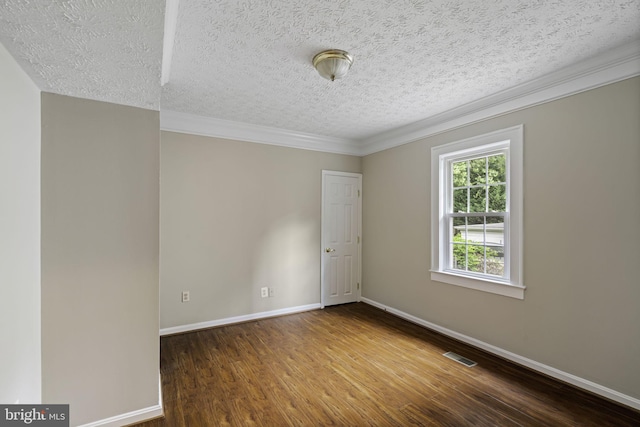 empty room with a textured ceiling, wood finished floors, visible vents, baseboards, and crown molding