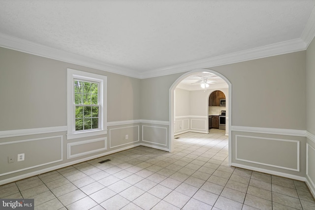 unfurnished room featuring arched walkways, a textured ceiling, light tile patterned flooring, and a decorative wall