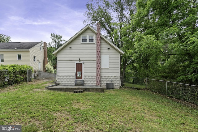 rear view of house with a lawn, a chimney, a fenced backyard, and central air condition unit