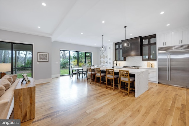 kitchen with a center island with sink, a breakfast bar area, light hardwood / wood-style flooring, and stainless steel built in fridge