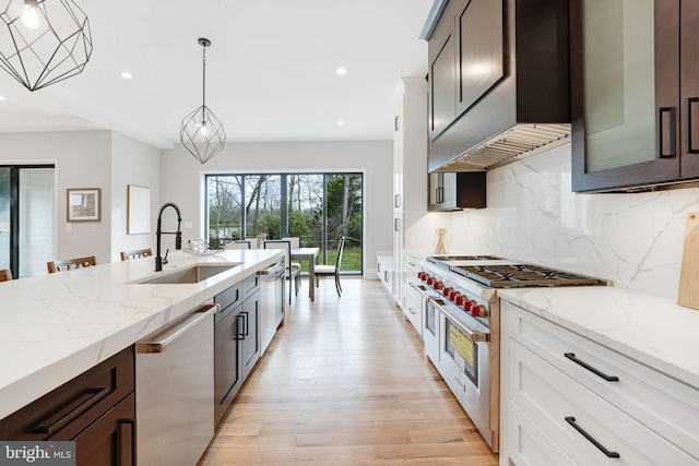 kitchen featuring pendant lighting, appliances with stainless steel finishes, light wood-type flooring, and white cabinetry