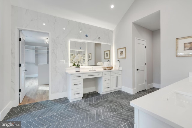 bathroom with wood-type flooring, vanity, and vaulted ceiling