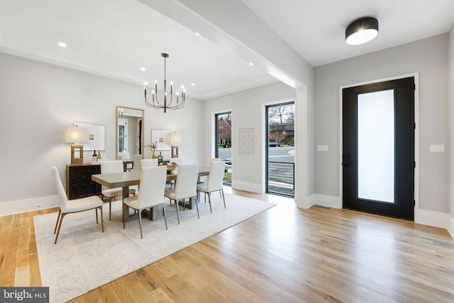 dining room with light hardwood / wood-style floors and a notable chandelier