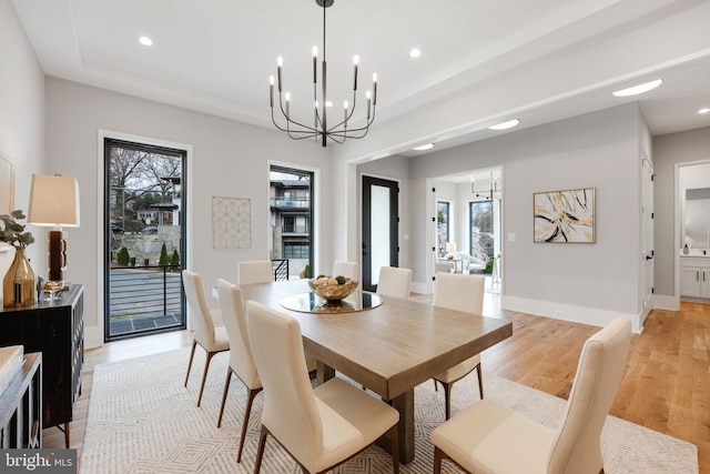 dining room with light wood-type flooring and an inviting chandelier