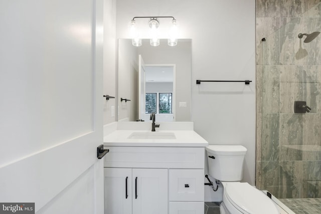 bathroom featuring tiled shower, vanity, and toilet