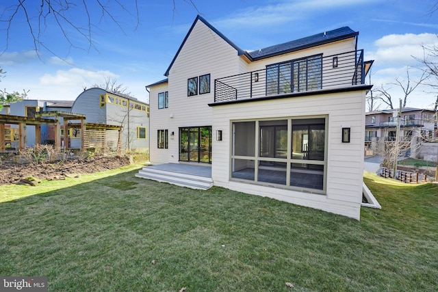 back of house featuring a lawn and a balcony