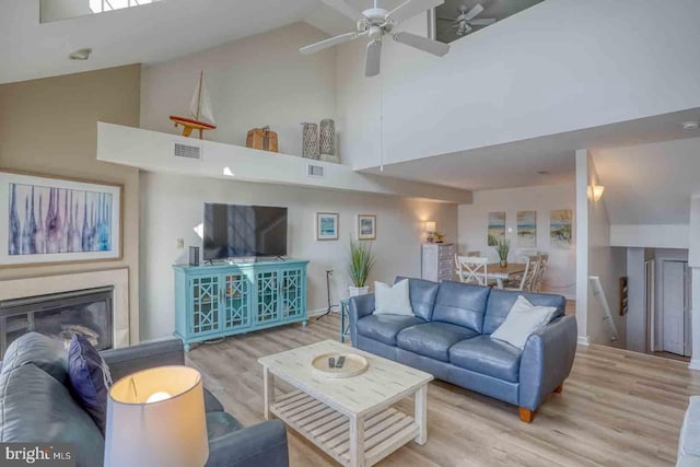 living room with light hardwood / wood-style floors, ceiling fan, and high vaulted ceiling