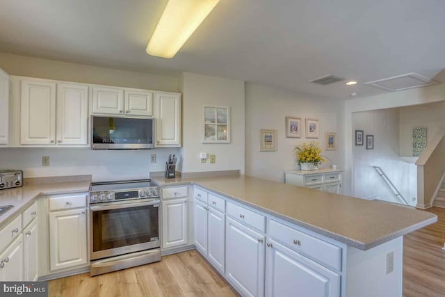 kitchen featuring appliances with stainless steel finishes, light wood-type flooring, kitchen peninsula, and white cabinetry