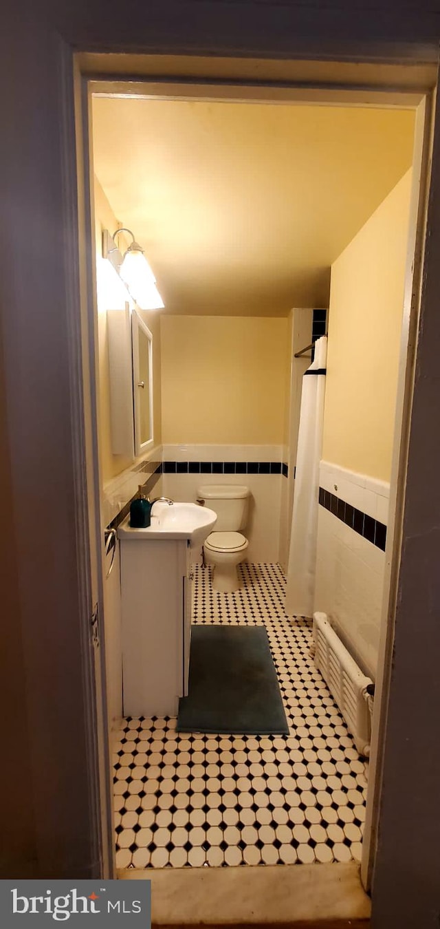 bathroom with tile walls, vanity, and toilet